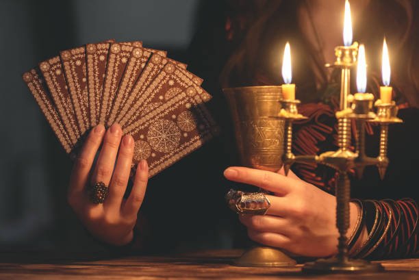 Fortune teller with deck of tarot cards in the light of burning table. Séance Tarot – 30 minutes | 35 € – Image 1