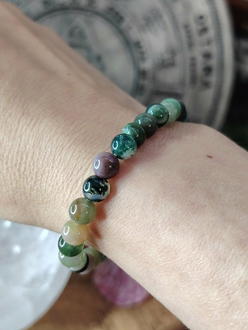 bracelet-agate-indienne-6-mm-perles-rondes-multicolores-vert-ocre-noir-violet-porte-au-poignet-photo-rapprochee-fond-interieur-gris-flou-paix-securite-interieure-calme-emotionnel.jpeg Bracelet agate indienne – Image 1
