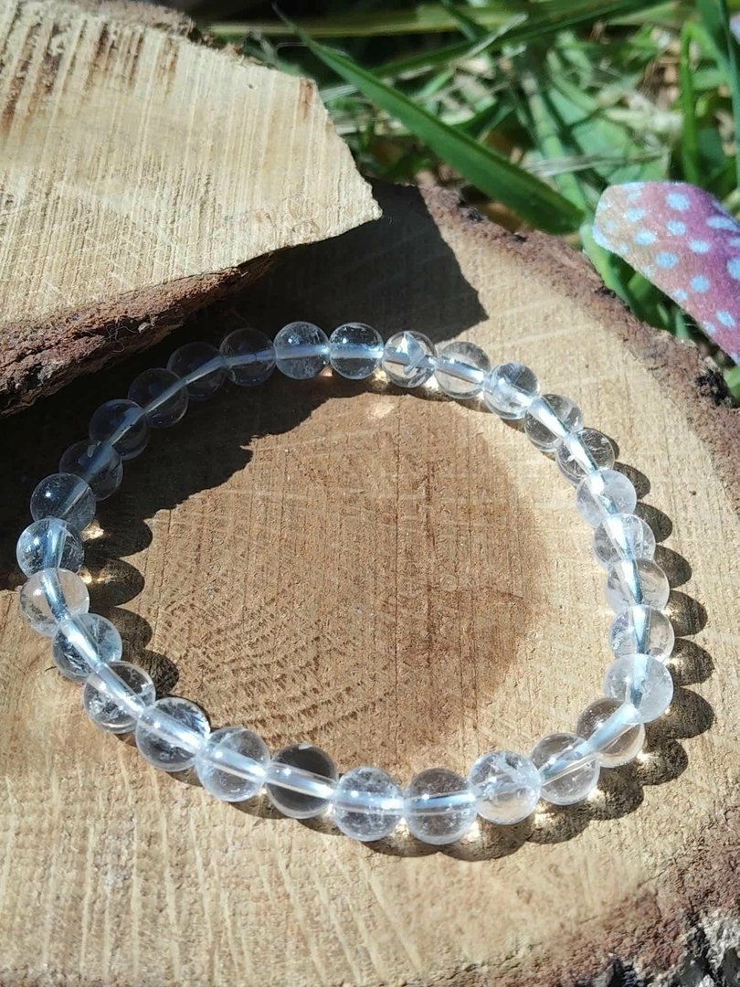 bracelet-cristal-de-roche-6-mm-perles-transparentes-polies-en-cercle-sur-rondin-de-bois-naturel-lumiere-douce-clarte-d-esprit.jpeg Bracelet cristal de roche – Image 1