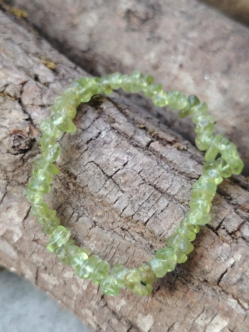bracelet-peridot-baroque-chips-verts-translucides-monte-sur-fil-elastique-presente-en-cercle-sur-un-tronc-de-bois-aux-veinures-marquees-en-lumiere-naturelle-ambiance-nature-foret.jpeg Bracelet péridot baroque – Image 1
